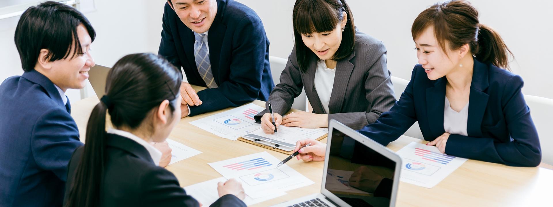 会議中にグラフ資料を見ながら議論するビジネスパーソンたち
