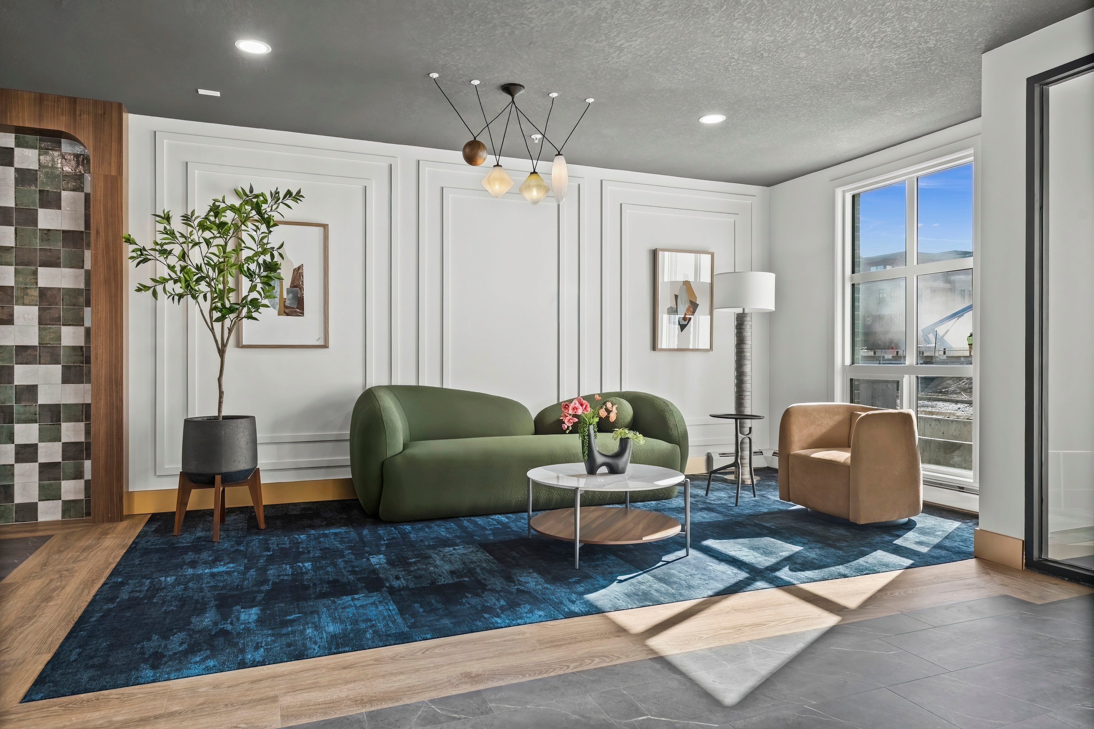 Dean's Landing lobby lounge by HAUS Interiors with moss boucle sofa, leather chairs and tall windows, University District, Calgary