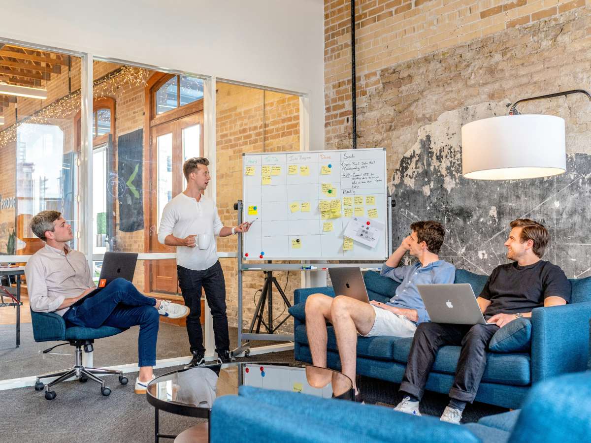 a team of men analyzing some information on a whiteboard, inside a living room