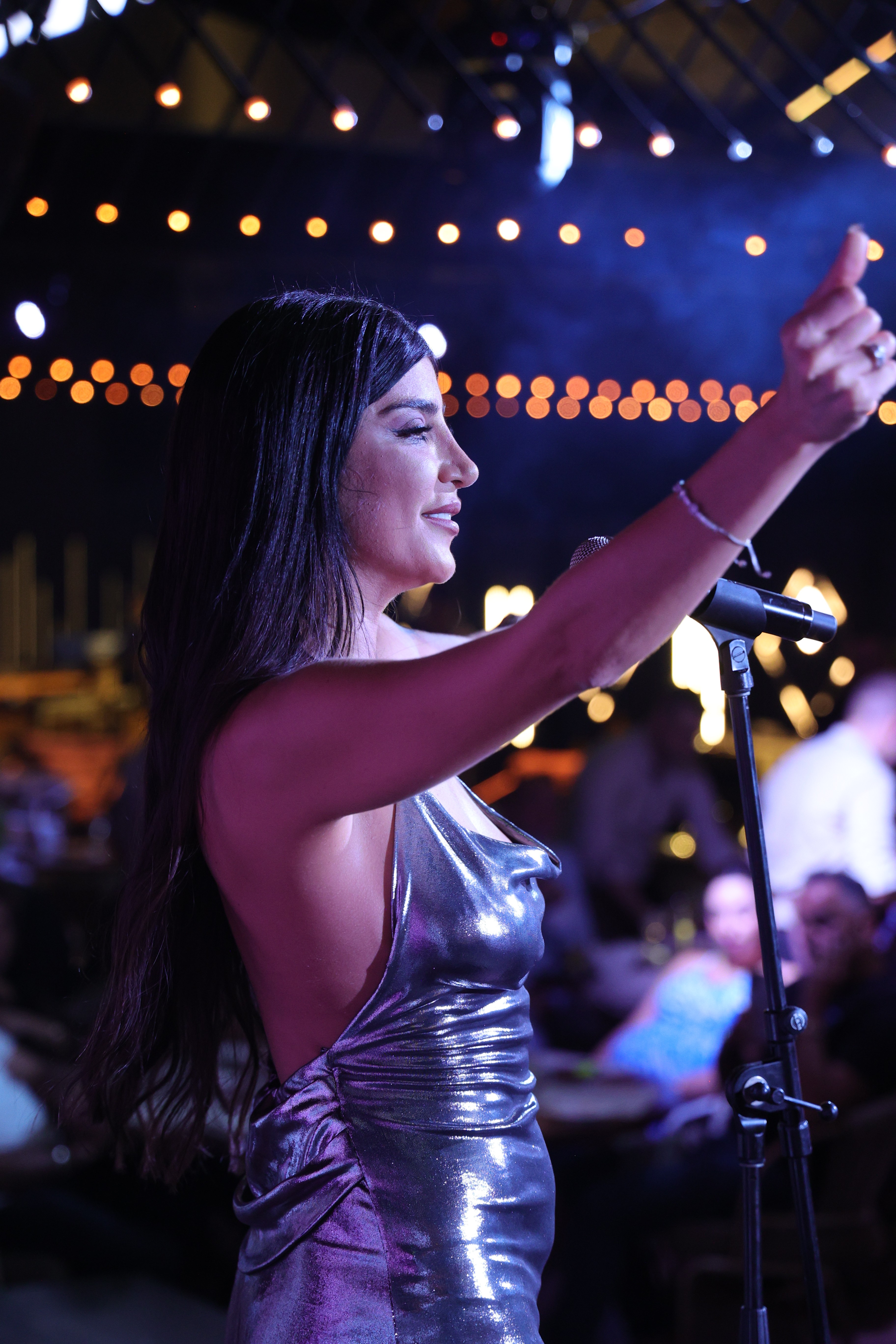 Smiling young man with curly hair, wearing a dark hoodie, against a softly lit background.