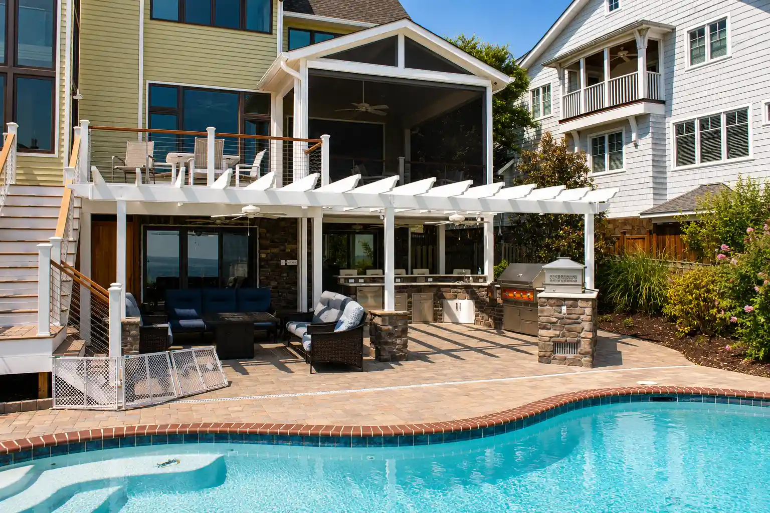 Renovated backyard with covered patio, outdoor kitchen, upper deck, screened porch, stonework, and swimming pool.