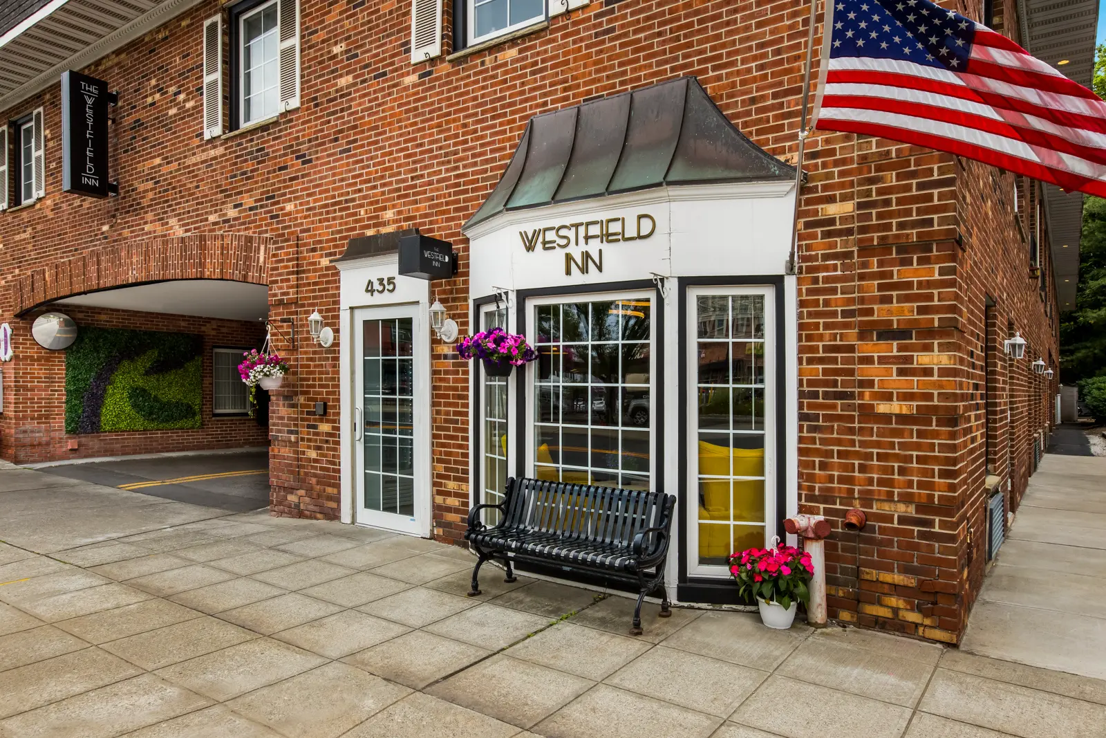 Exterior of The Westfield Inn with bench and American flag.
