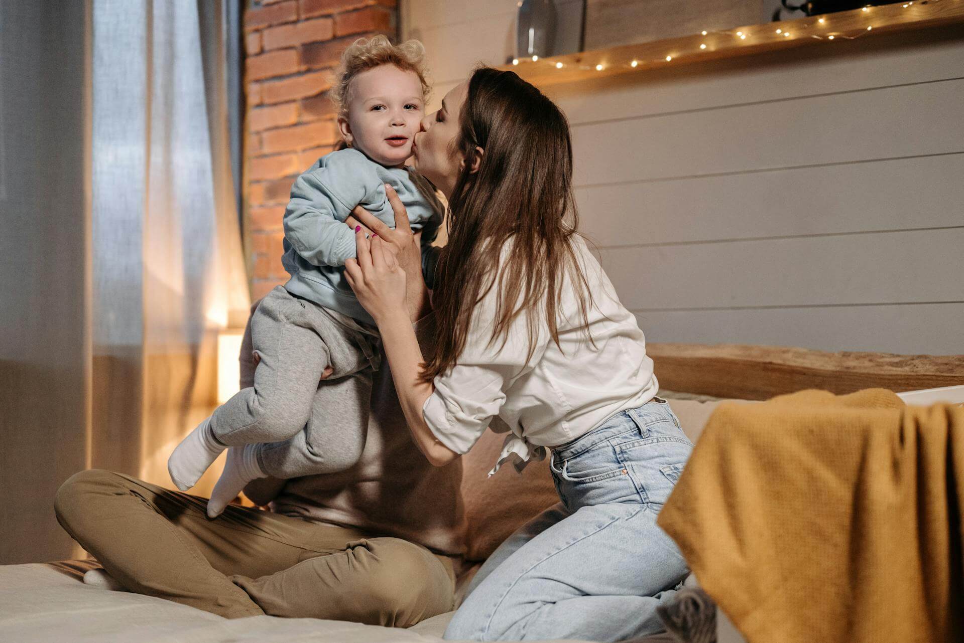 A woman and a baby sit together on a cozy bed, sharing a tender moment of connection and warmth