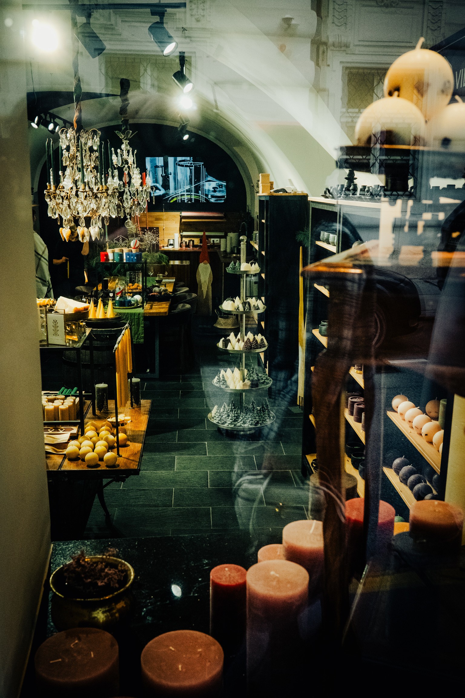 Escaparate de una tienda de velas con lámpara de araña y reflejos en el cristal