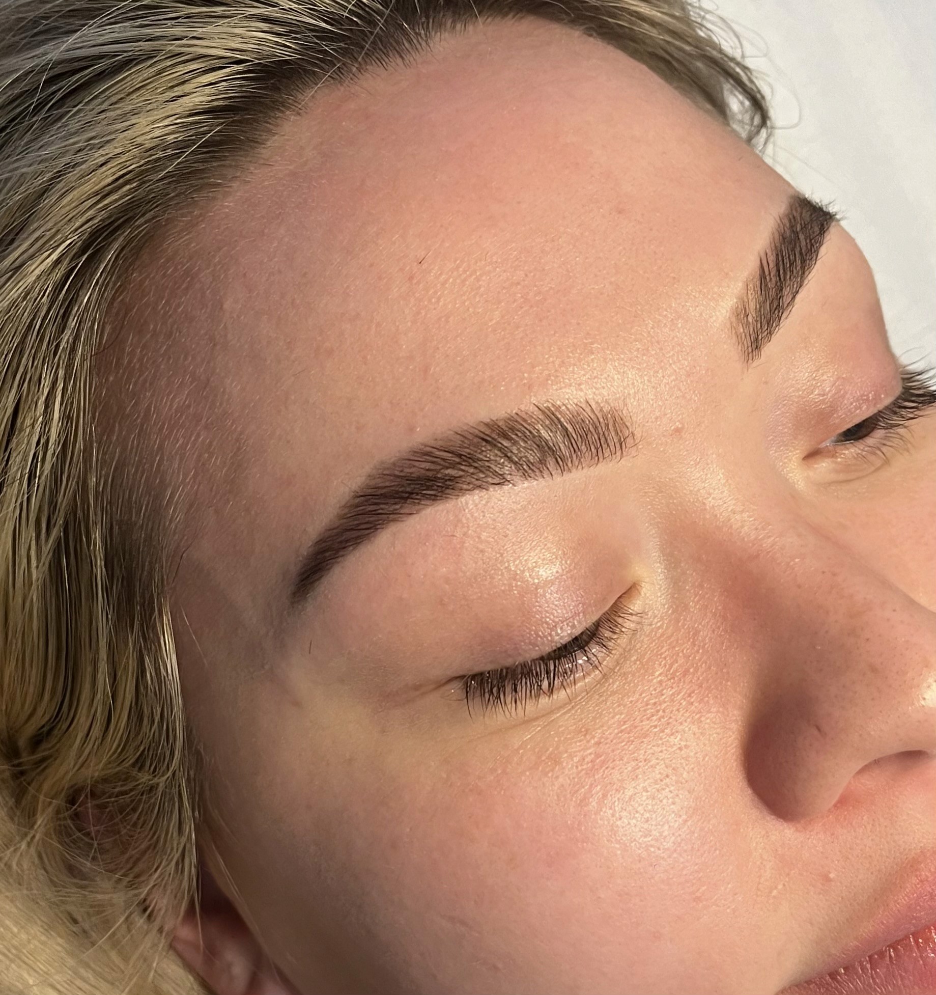 Close-up of a person's face with closed eyes and light-colored hair, relaxed or resting.