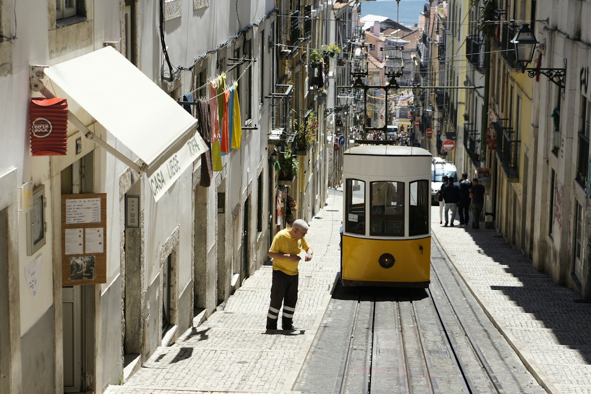 Yellow tram climbing a narrow street in Lisbon