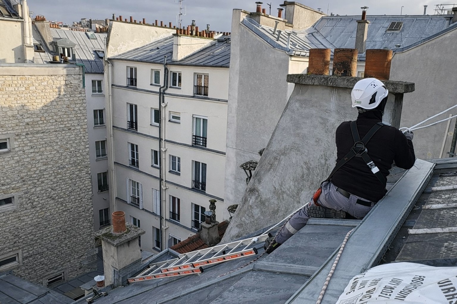 Travaux sur corde en toiture à Paris avec cordiste sécurisé sur toit en zinc d’immeuble haussmannien