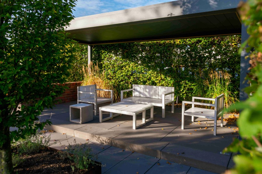 Covered outdoor dining patio with modern seating and paved stone flooring.