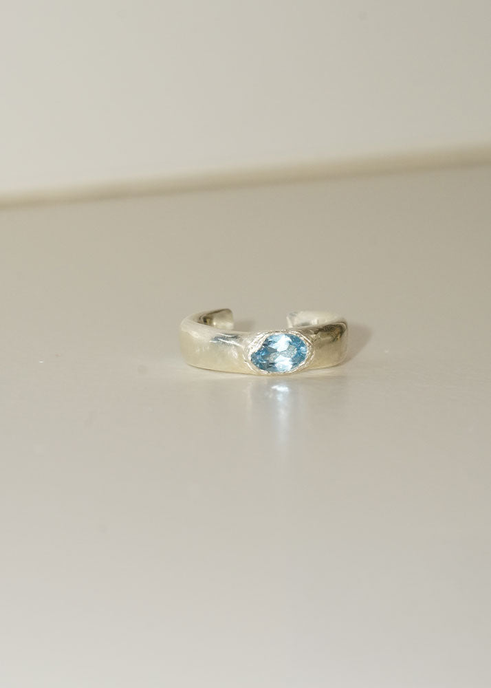 Silver ring with a blue gemstone on a light gray background