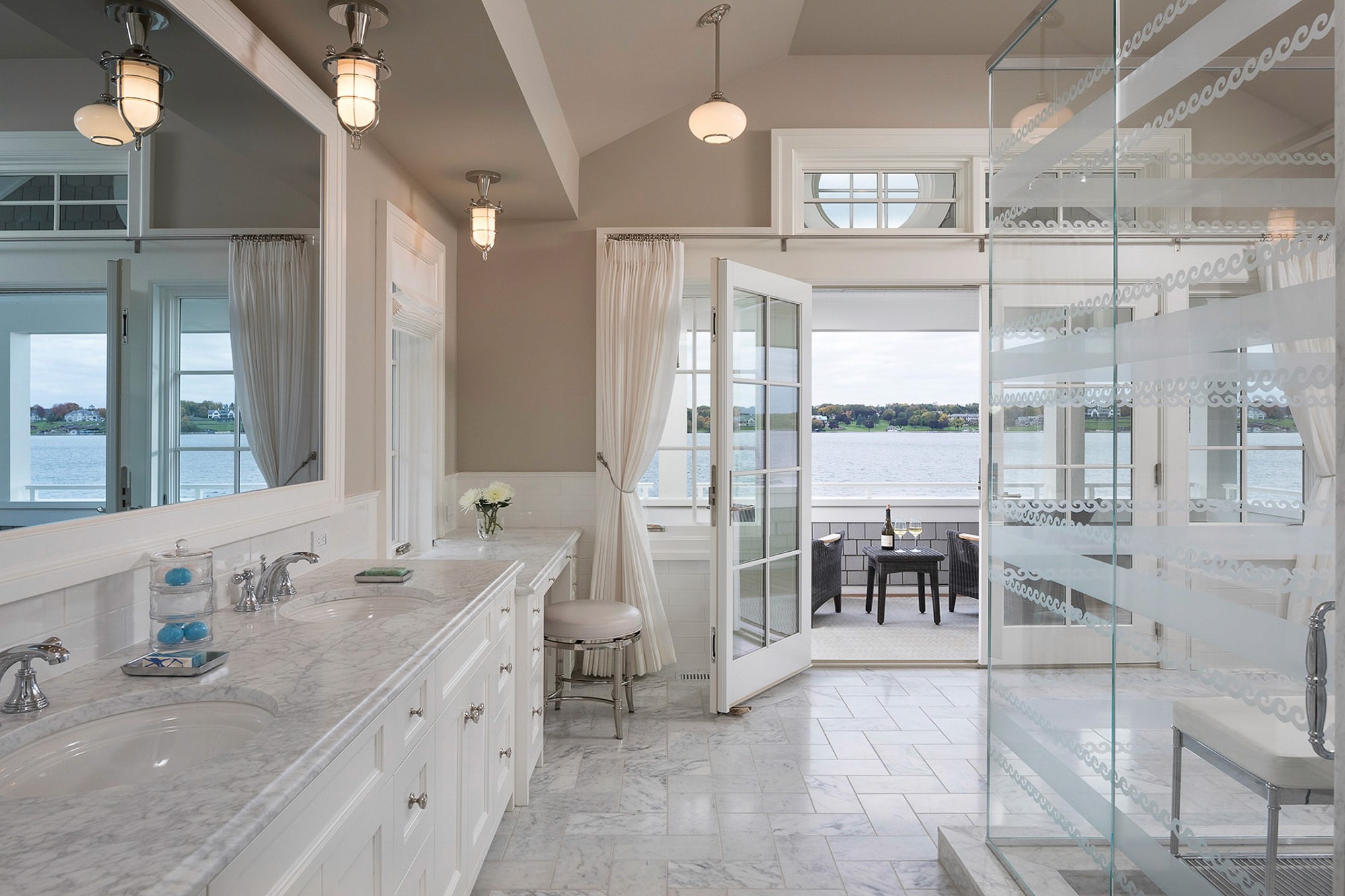 Luxurious marble bathroom with an open-door view of a lake.