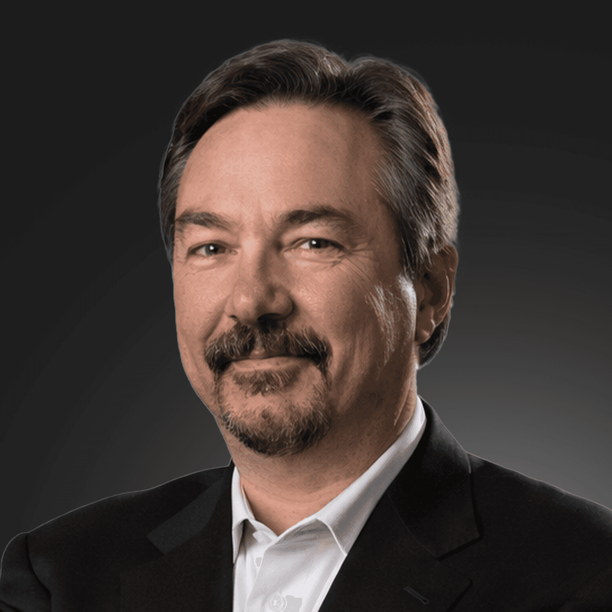 A young woman with long dark hair smiles confidently while crossing her arms in a modern indoor setting.