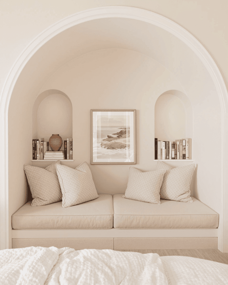Cozy reading nook with beige cushions, bookshelves, and framed wall art.
