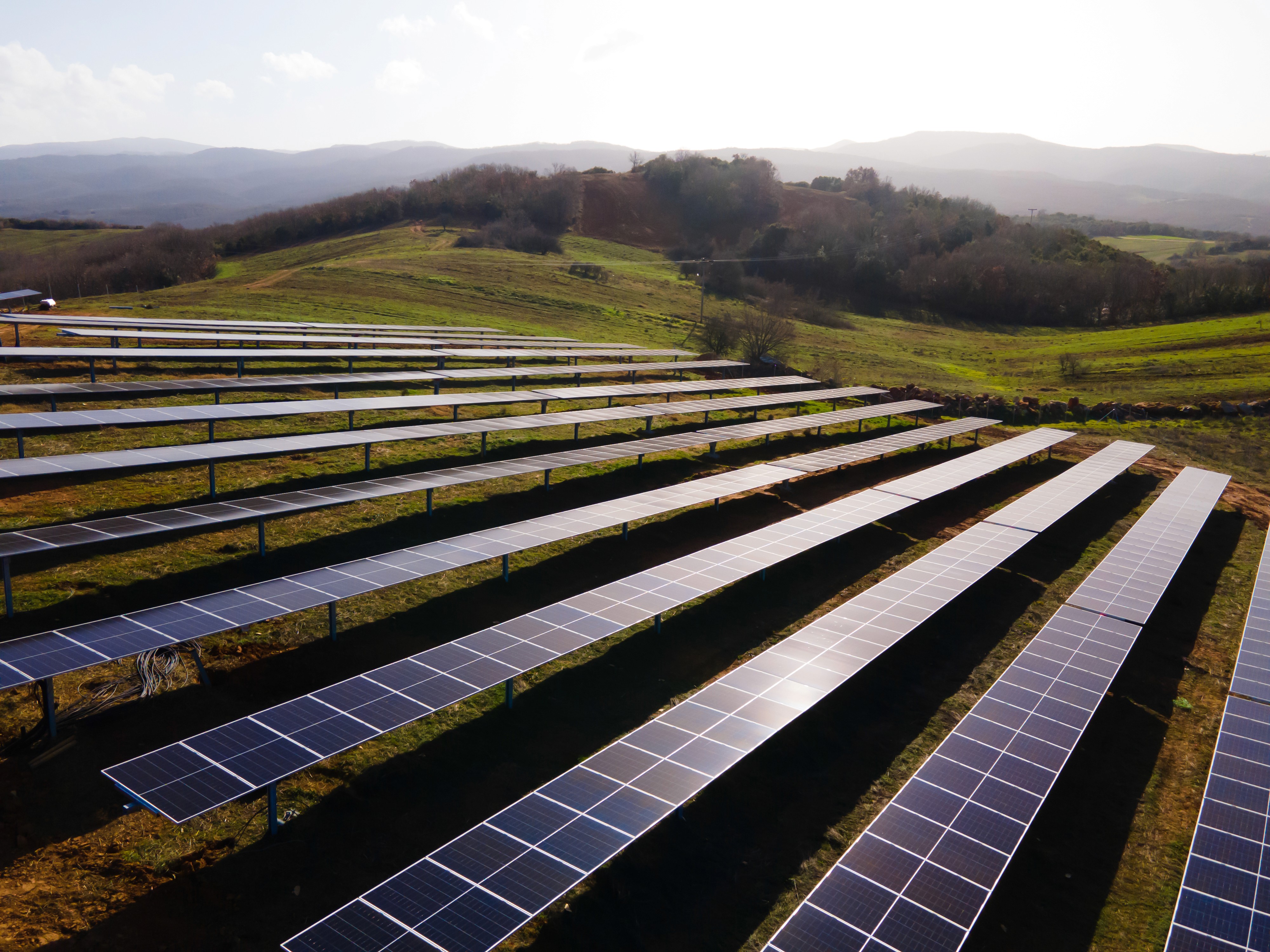 Elevated view of ground-mounted solar panel rows across hilly terrain in large-scale photovoltaic installation