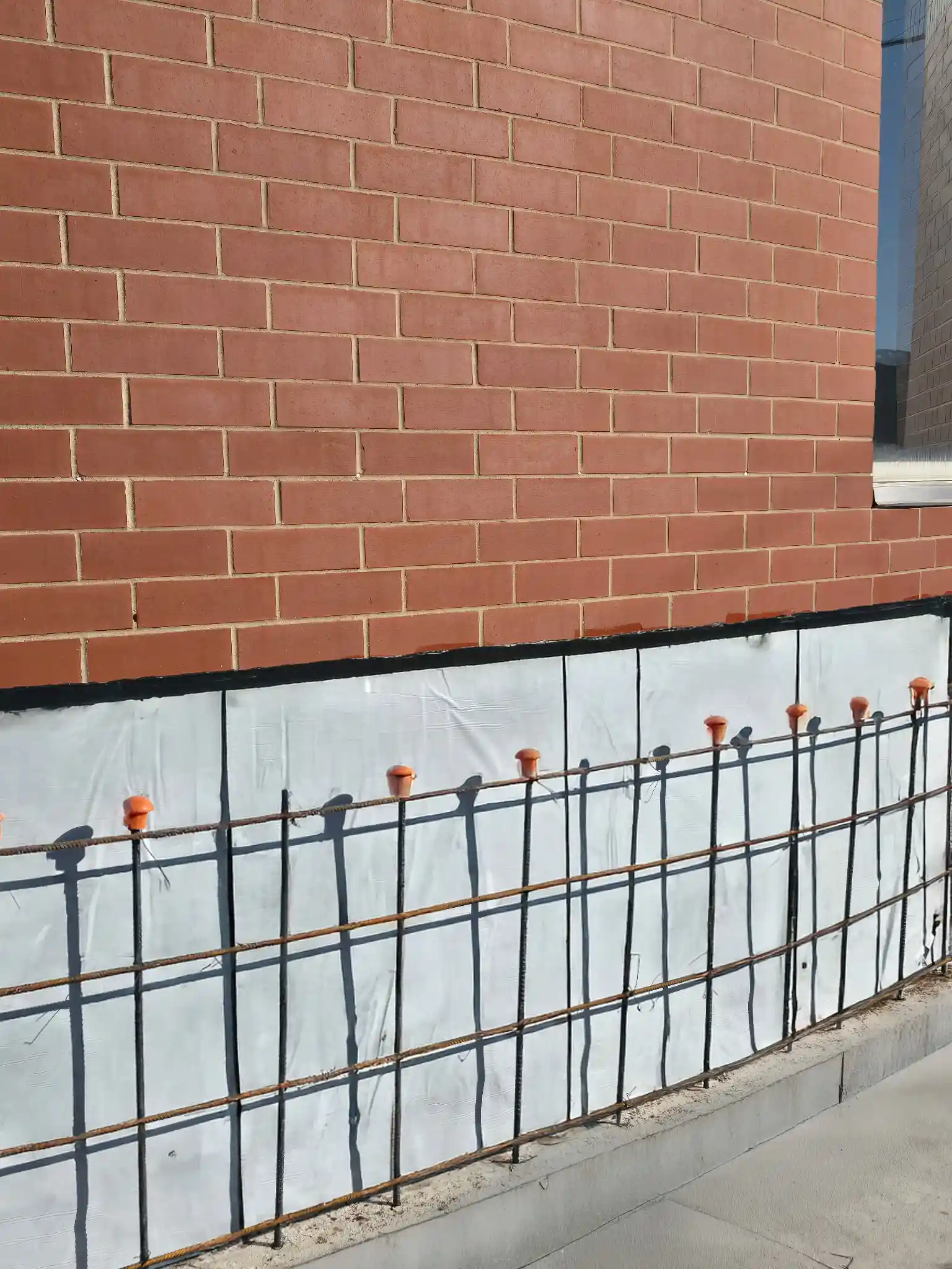 Peel-and-stick waterproofing covering a building foundation