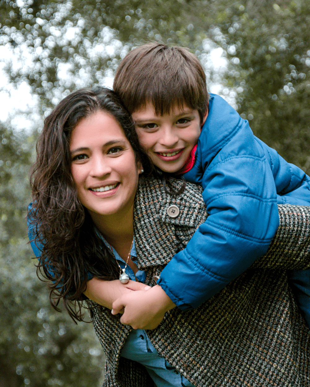 Smiling female teacher in glasses with arms crossed in a bright, colorful classroom