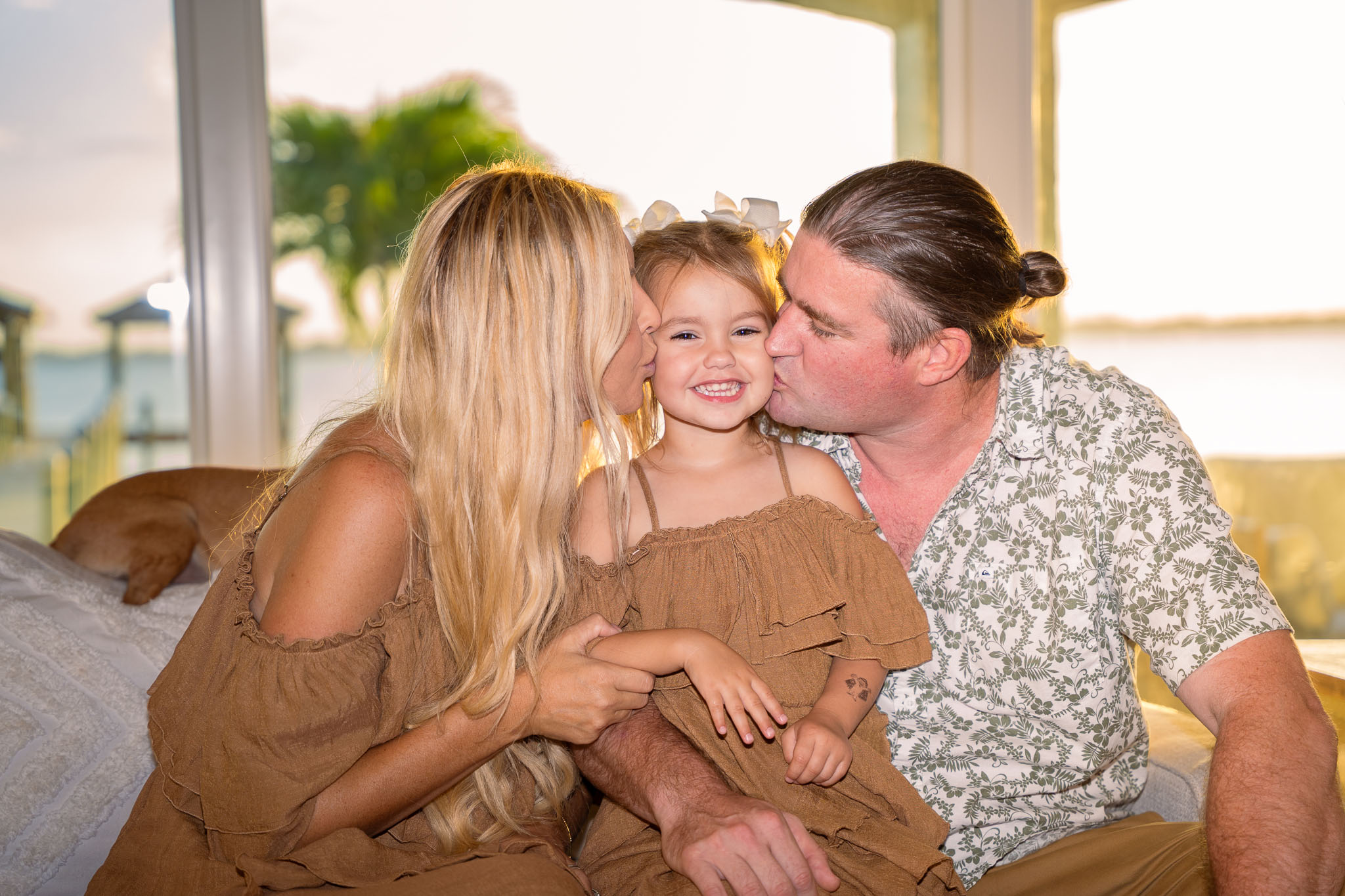  a mom and dad kissing their daughter's cheeks on each side