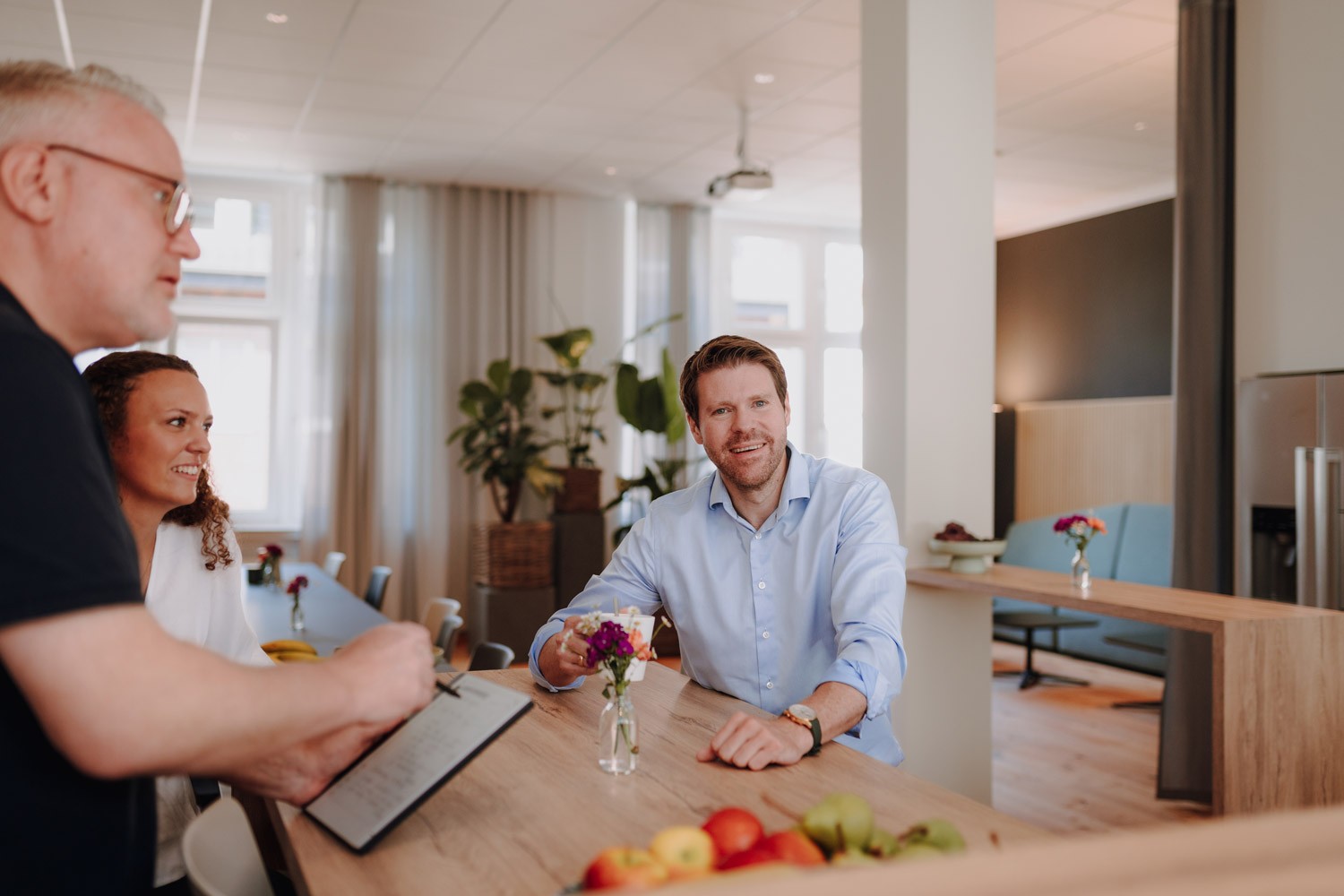 Beratungssituation bei SLB: Drei Personen sitzen sich an einem Tisch gegenüber und sprechen miteinander.