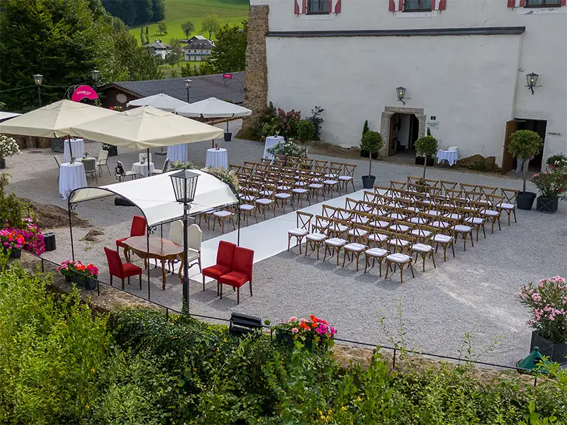 A three-tiered wedding cake adorned with soft pink roses and delicate floral arrangements against a bright background.