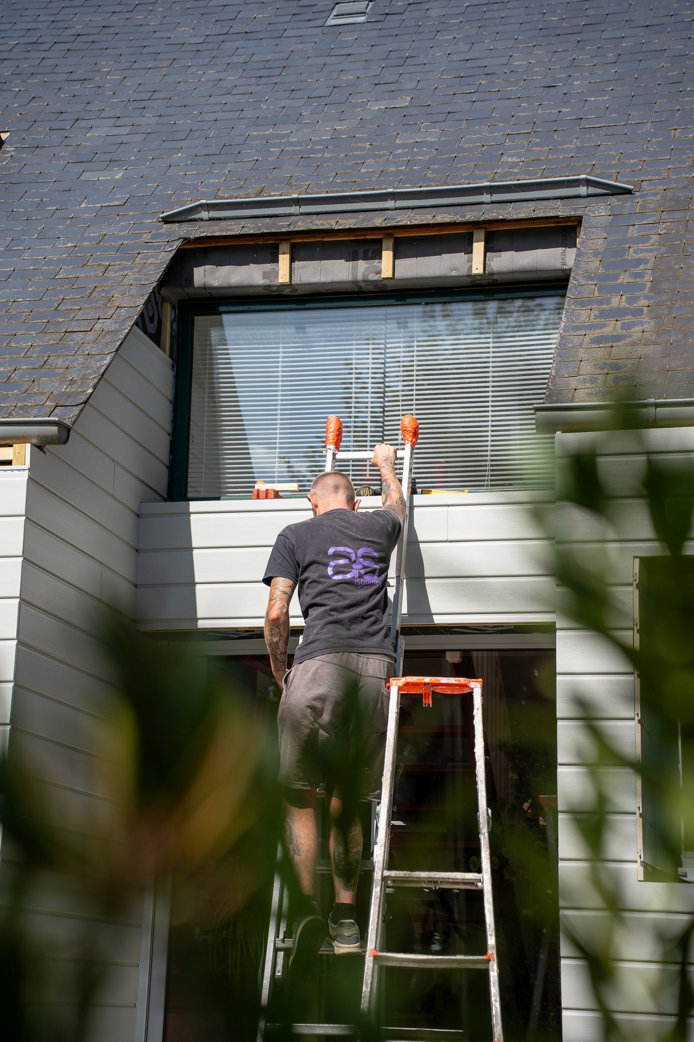 Artisan menuisier AS Rénov installant des lames de bardage bois sur la façade isolée d'une maison en Bretagne