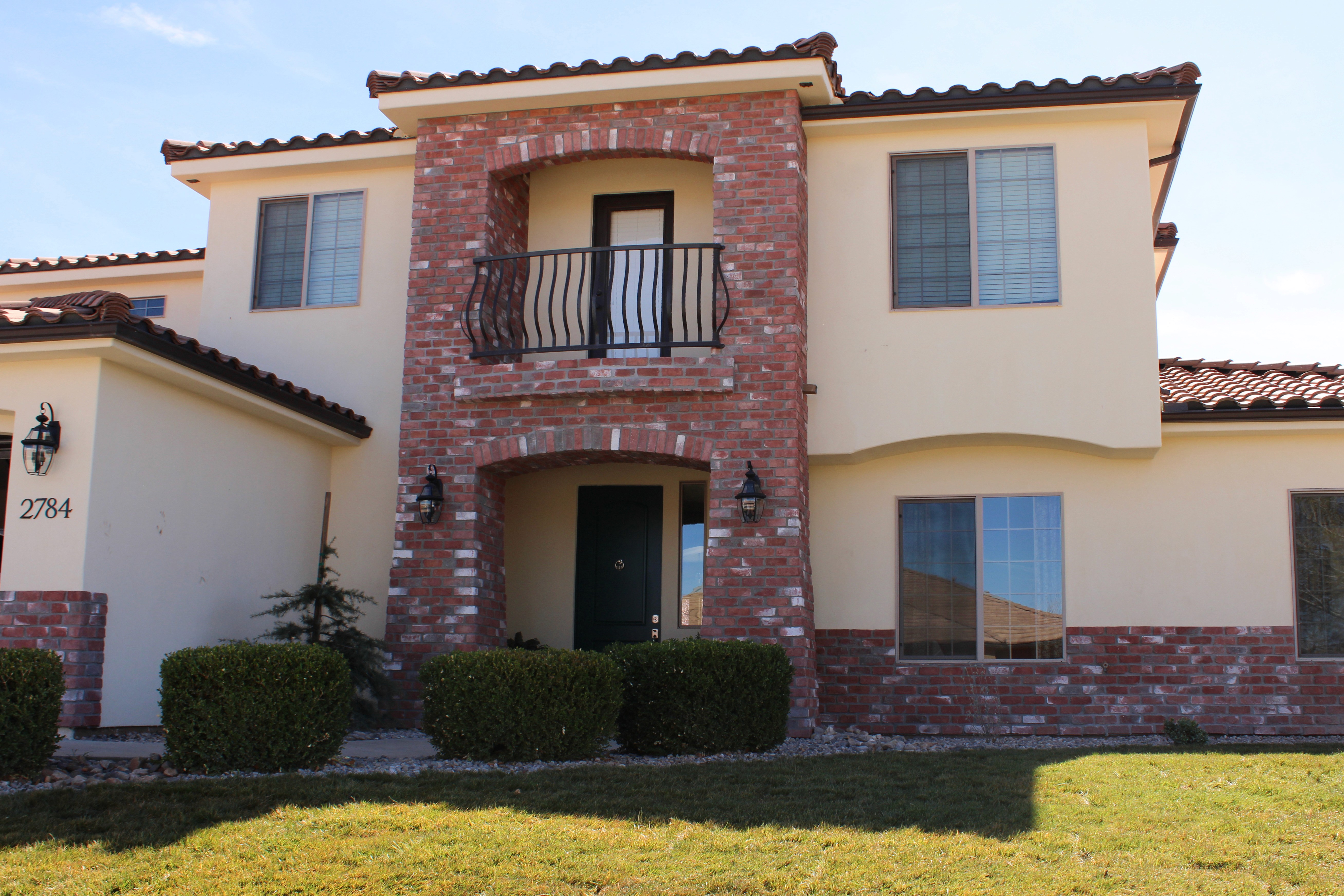 Front exterior of a Washington, Utah home with pale blue accents, red brick, and stucco finish