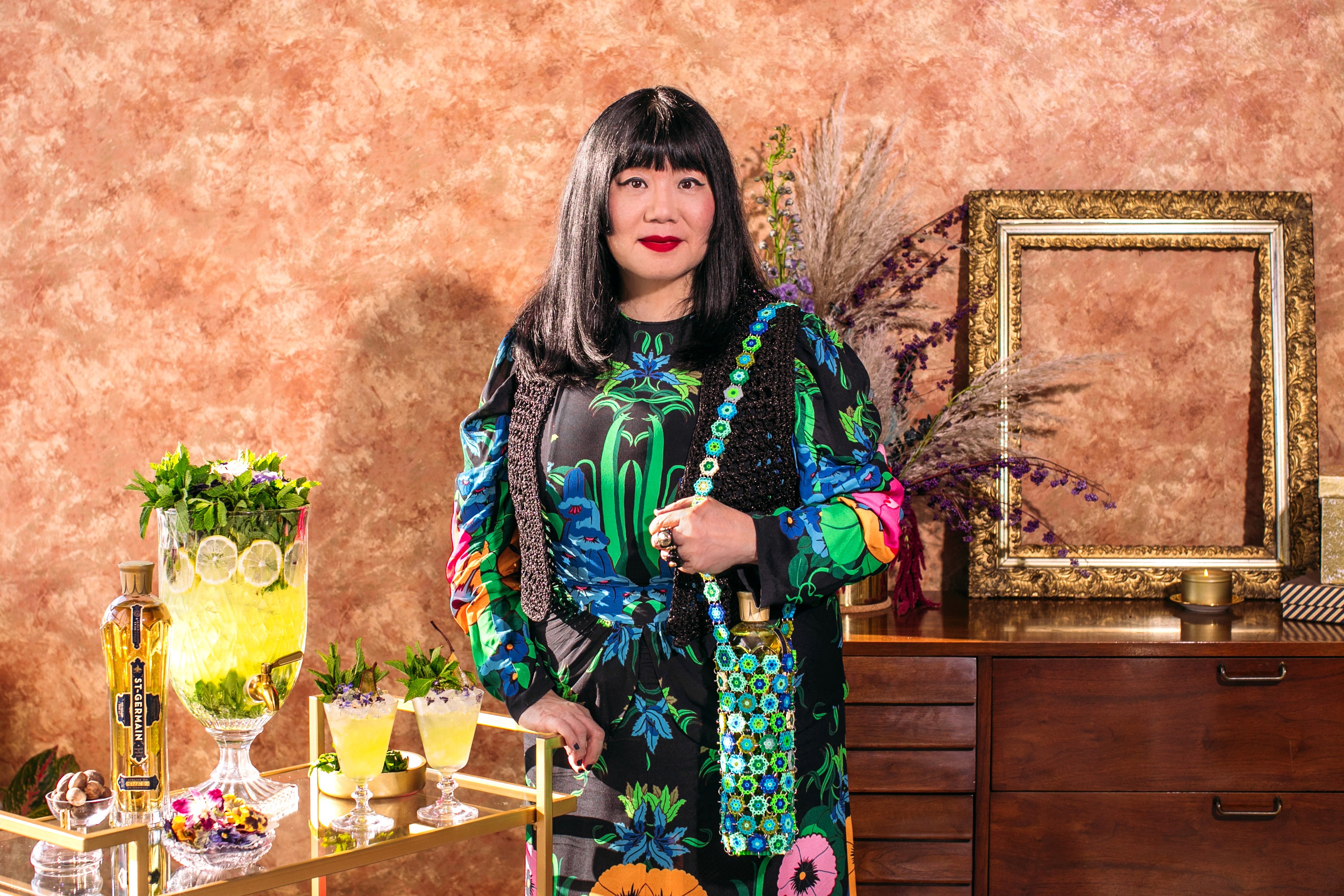 Anna Sui portrait with St-Germain cocktails and floral bottle tote