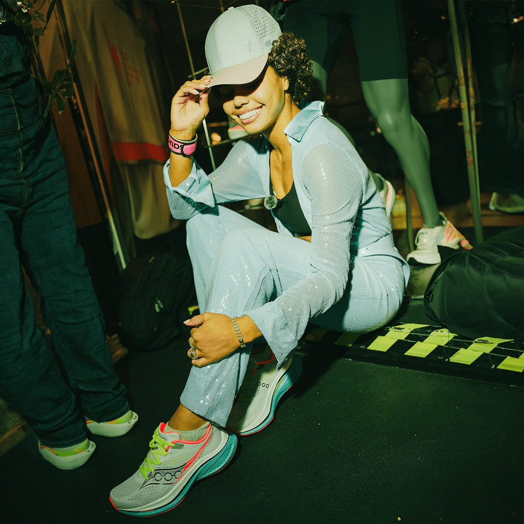 Editorial portrait of a bald model with a white clay mask on face and body, neutral backdrop.