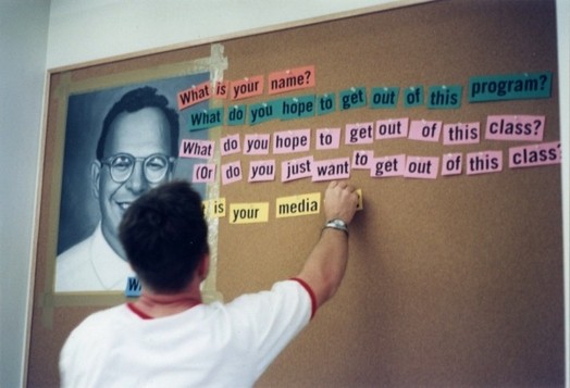 a young man writes sentences on cardboard with small pieces of paper with words printed on them