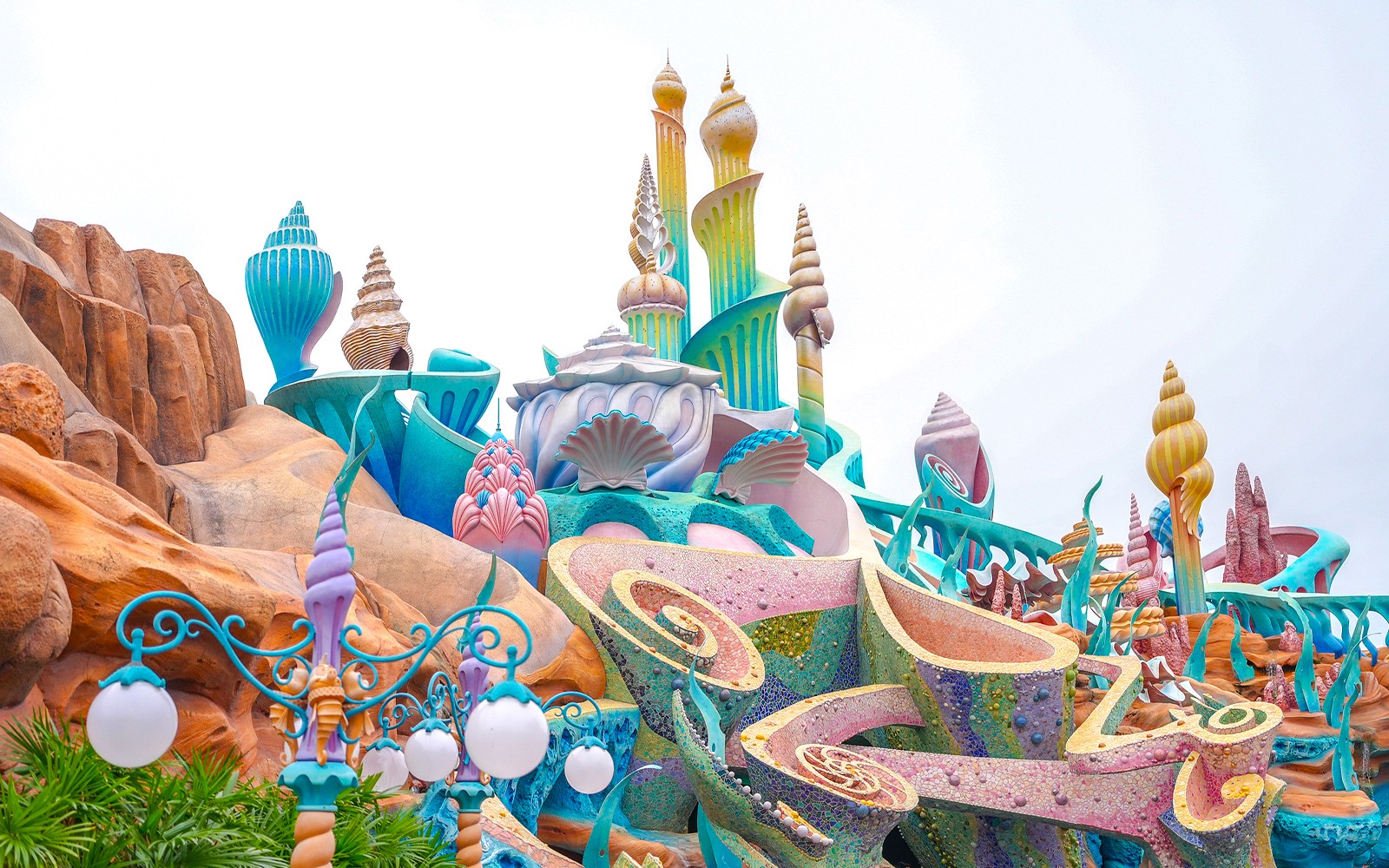 Tokyo Disneyland entrance with visitors and iconic Cinderella Castle in the background.