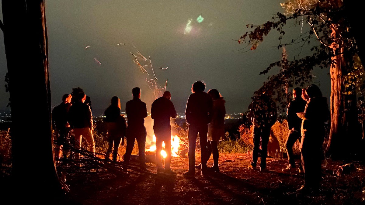 A group of colleagues gathered around a campfire during a company retreat