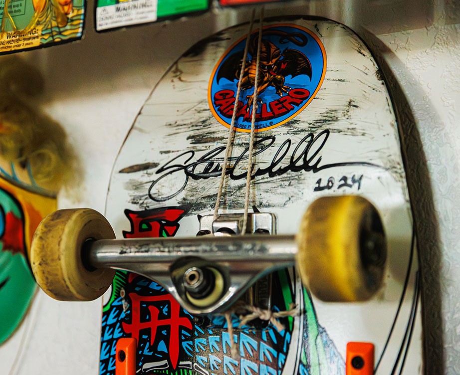 Close-up of a vintage Steve Caballero skateboard, featuring the classic Powell Peralta dragon graphic, worn wheels, and Caballero’s signature on the deck.