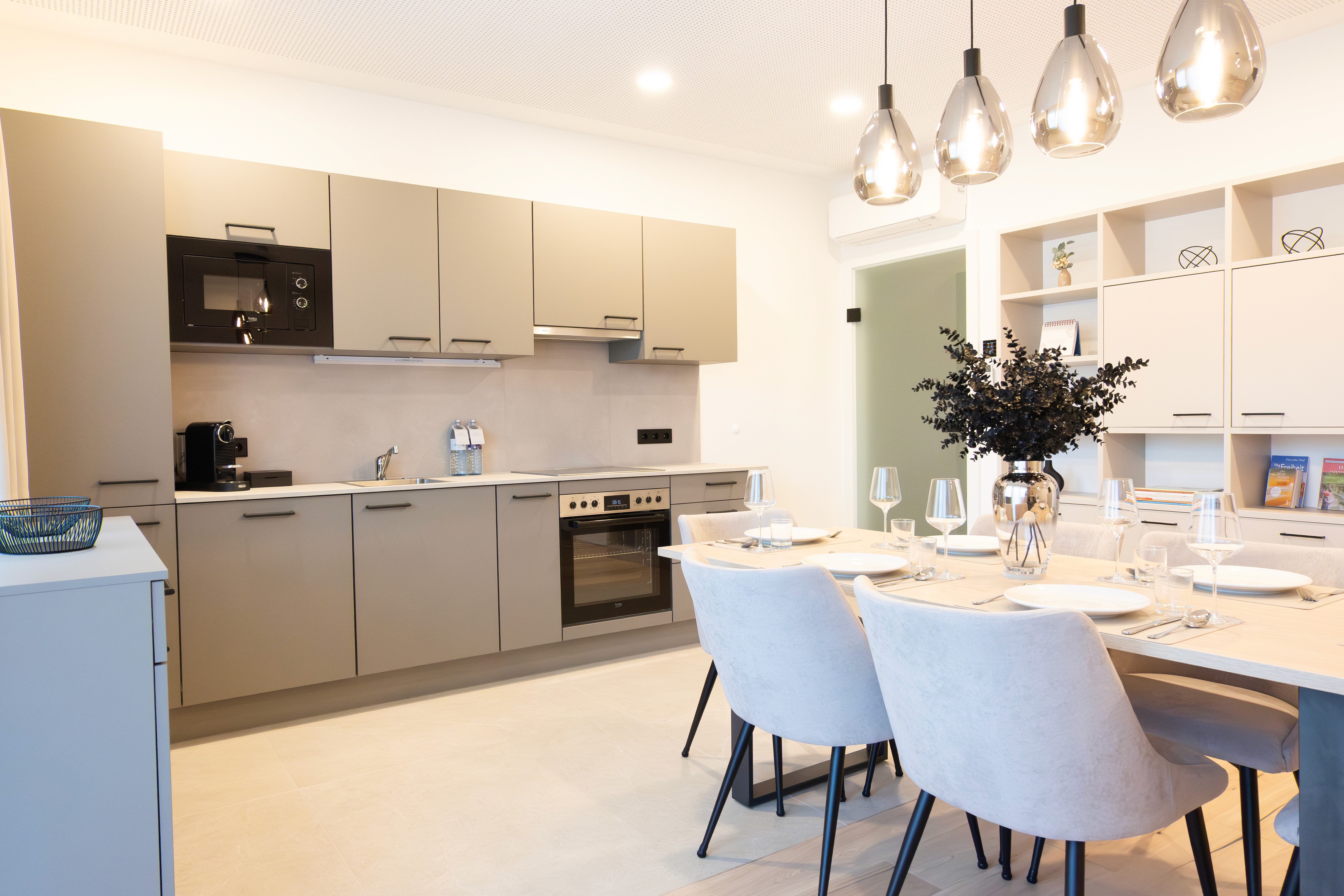 Moderne Küche mit Essbereich. Graue Schränke, Ofen, Esstisch & Stühle. Wohnungseinrichtung