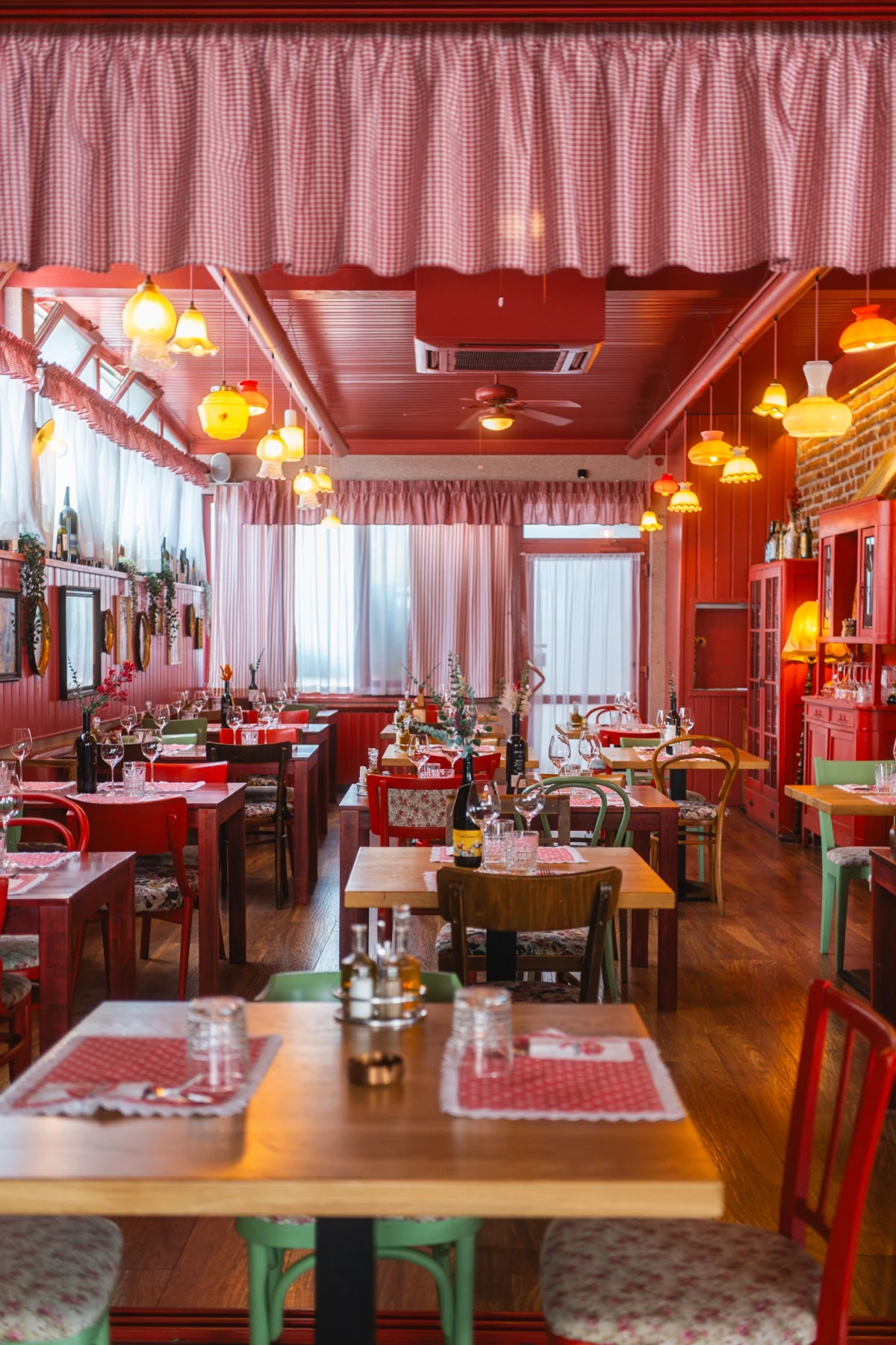 Unutrašnjost Bistroa Točkica s crvenim stolicama, kariranim stolnjacima i svjetiljkama