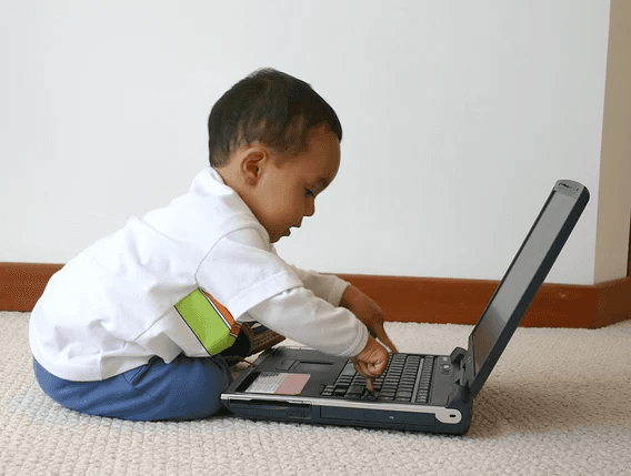 A child using a laptop computer on the floor.