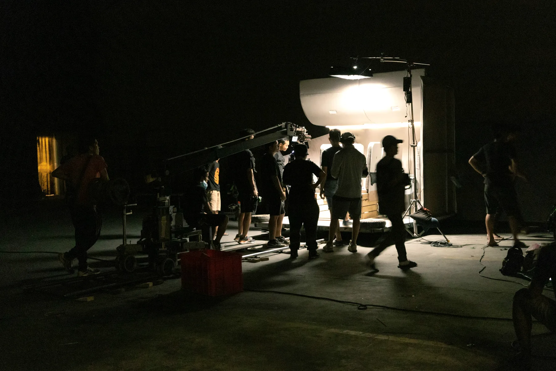 Film crew working around a lit trailer at night