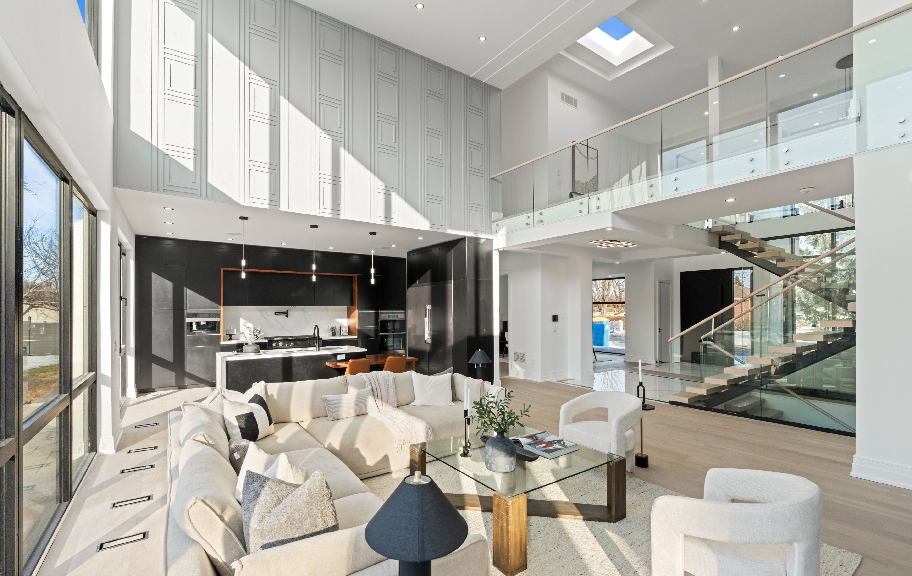 Modern indoor space with large glass doors, lush greenery, and a cozy seating area visible beyond.
