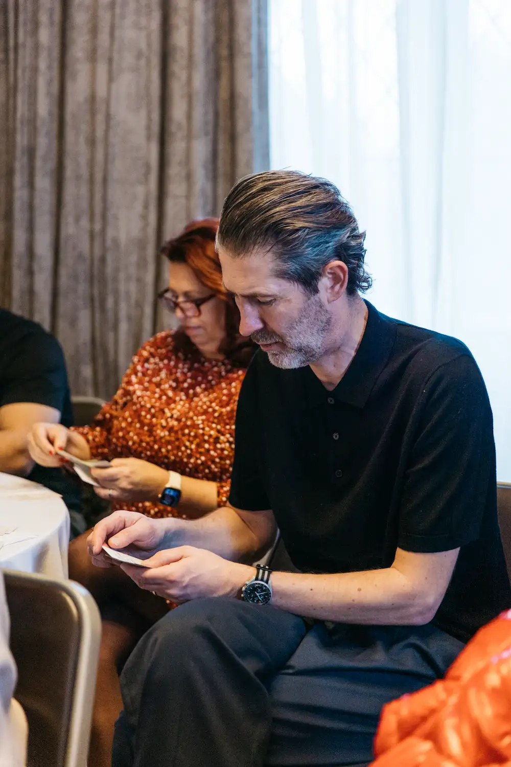 A person reading a book while another watches.