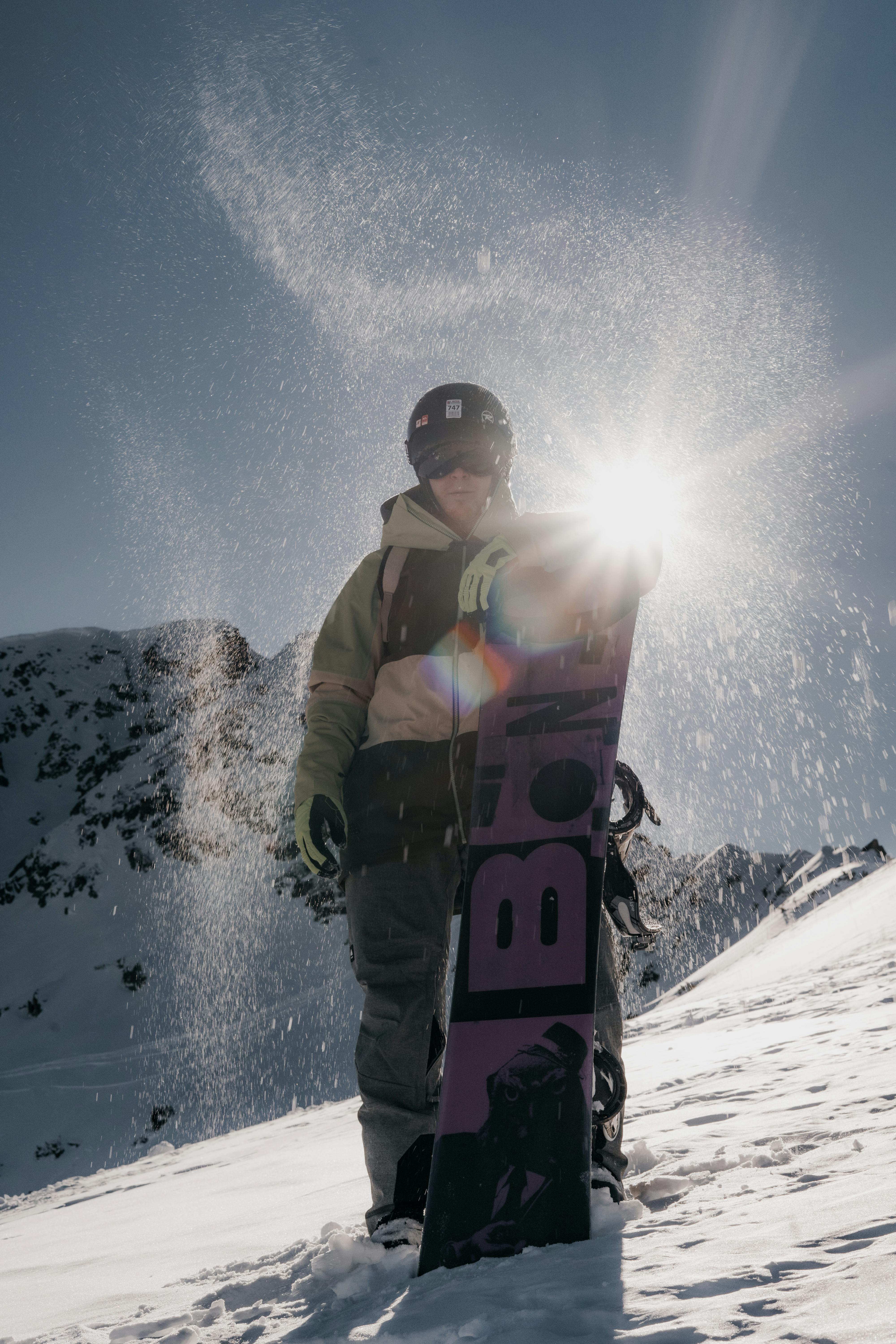 man in black jacket holding orange and black helmet