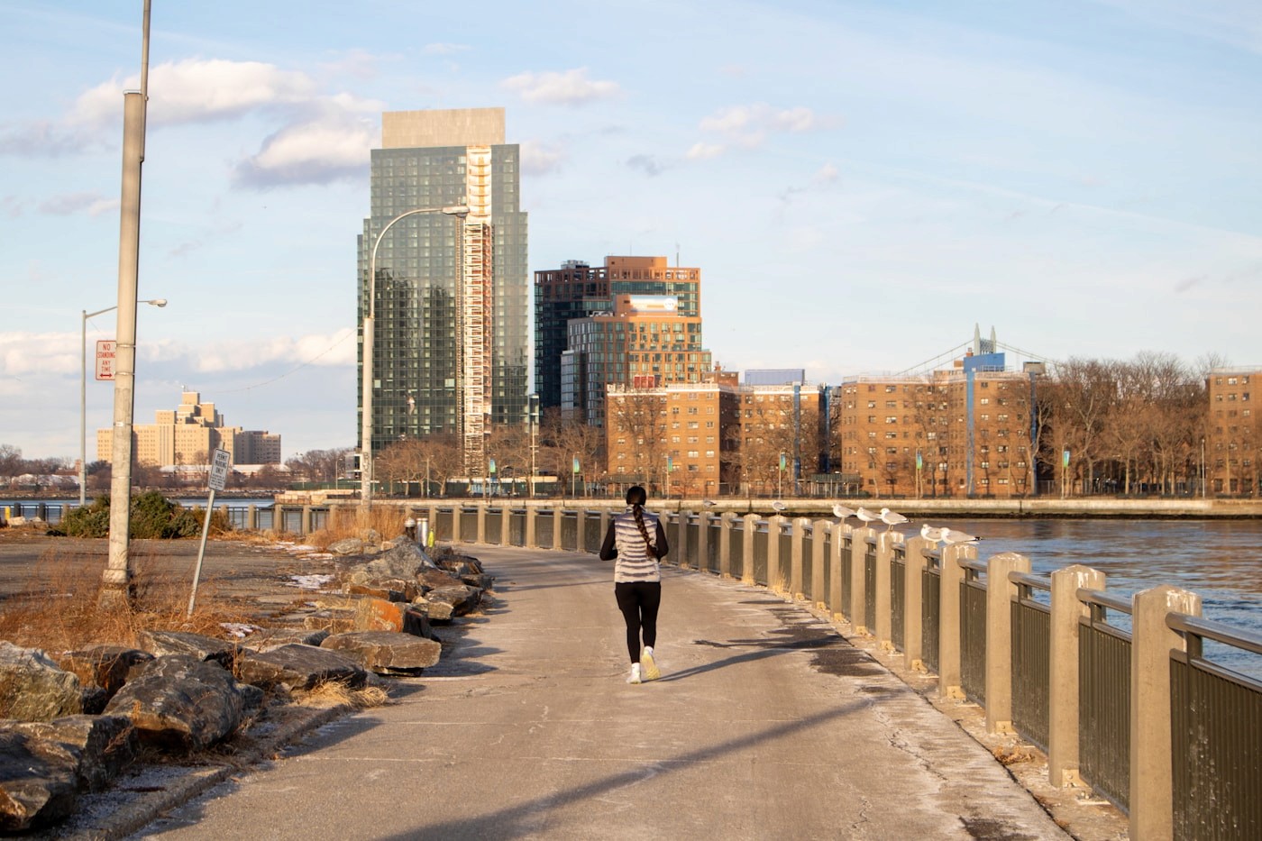 A woman jogging along a waterfront city path, representing everyday recreational runners