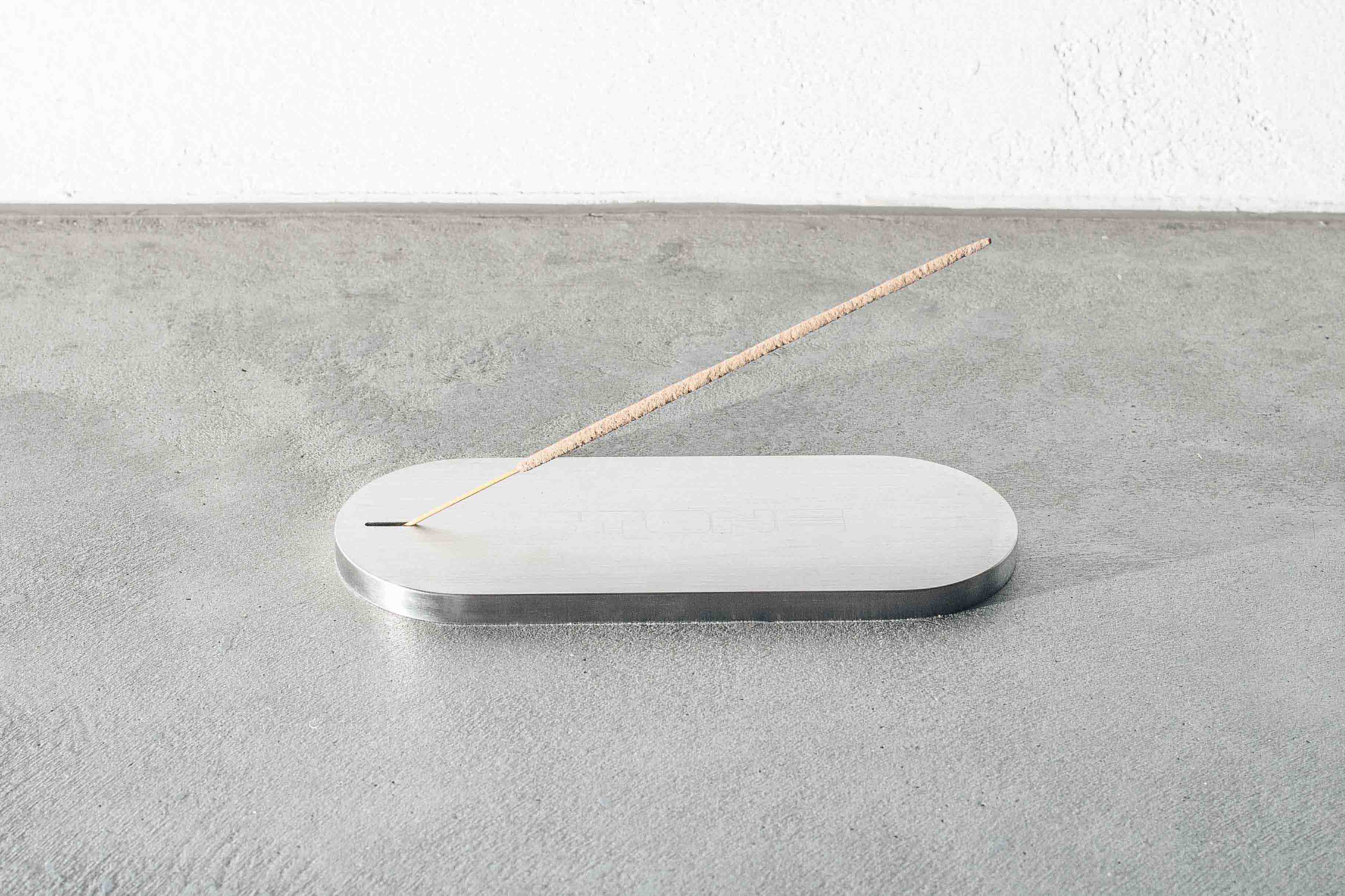 a metal incense holder on a concrete floor