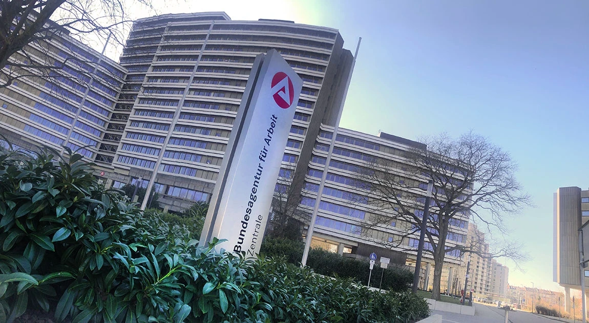 Gebäude der Bundesagentur für Arbeit in Nürnberg mit dem roten Logo auf einer Stele im Vordergrund.