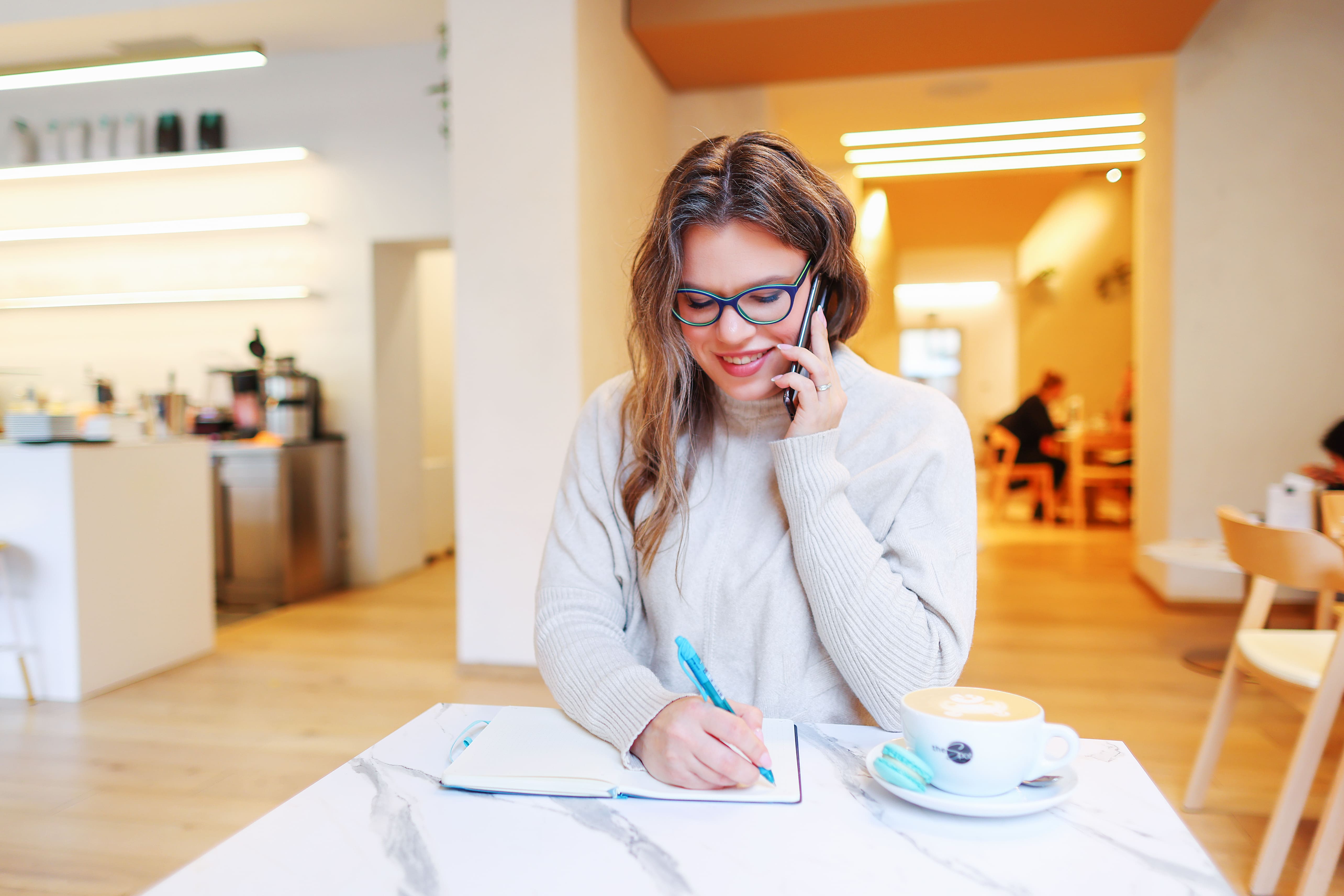 Shopify website designer consulting a client while taking notes in a cafe workspace