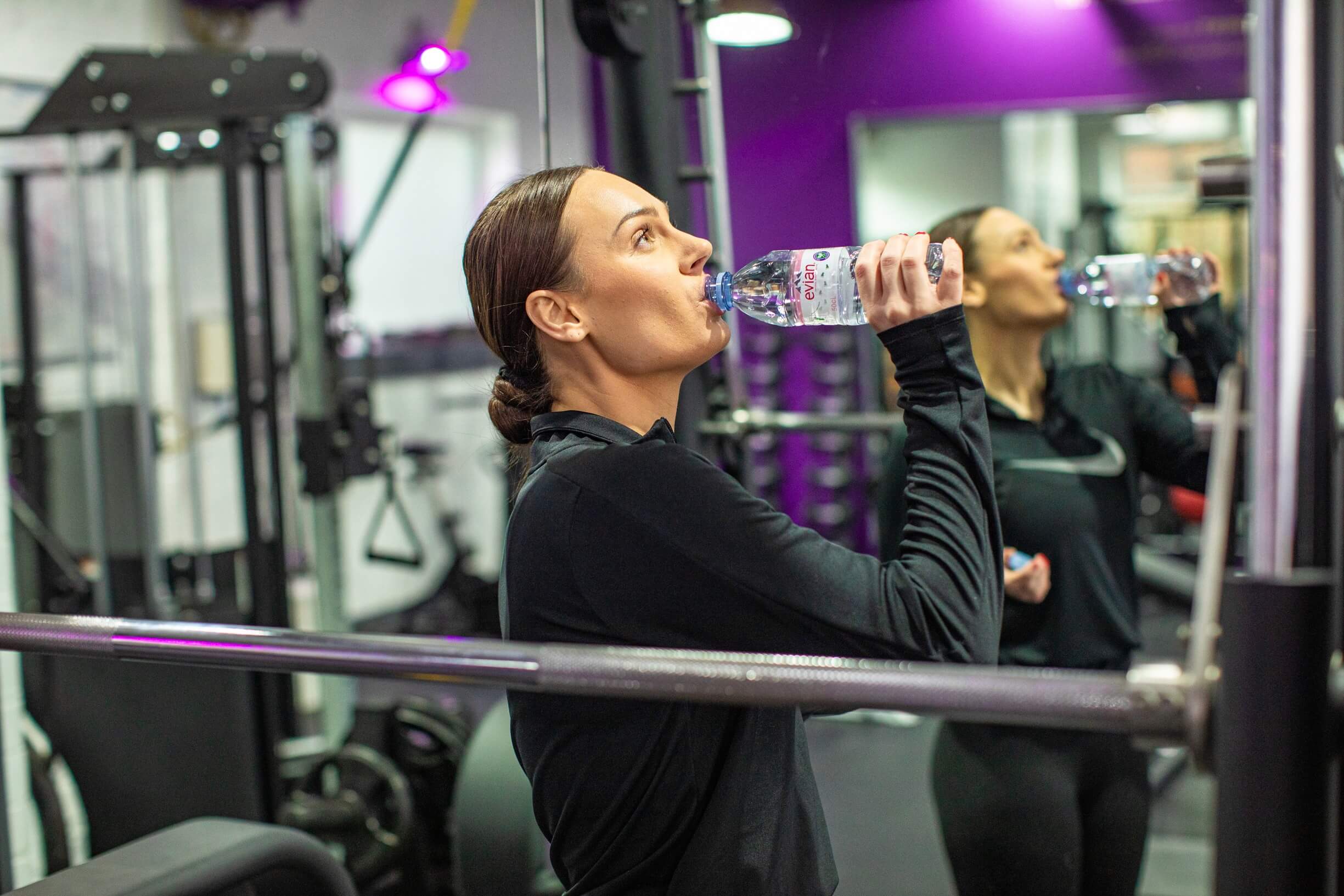 Woman drinking water from a bottle after an intense workout. 