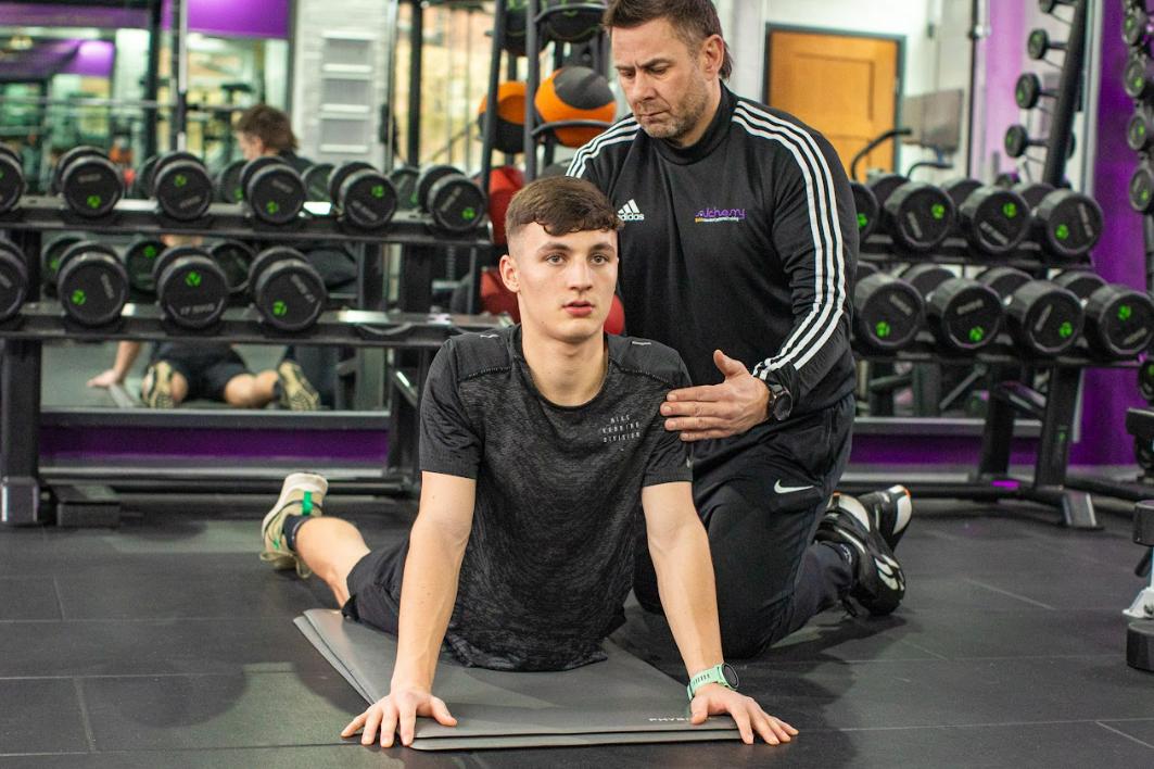 A man getting the proper posture with the help of an Alchemy fitness trainer following the right weight loss exercise plan