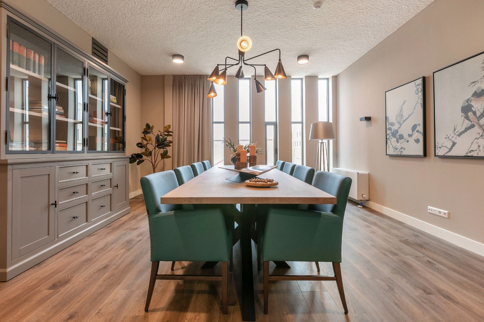 woonkamer met grote boekenkast en blauwe stoelen