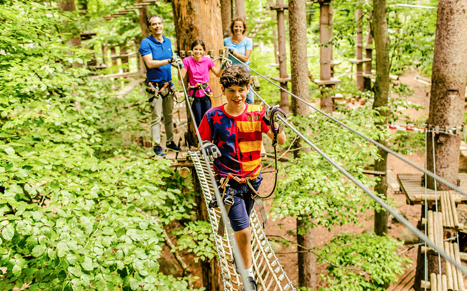 Family navigating a treetop rope course at Ropes Park Interlaken.