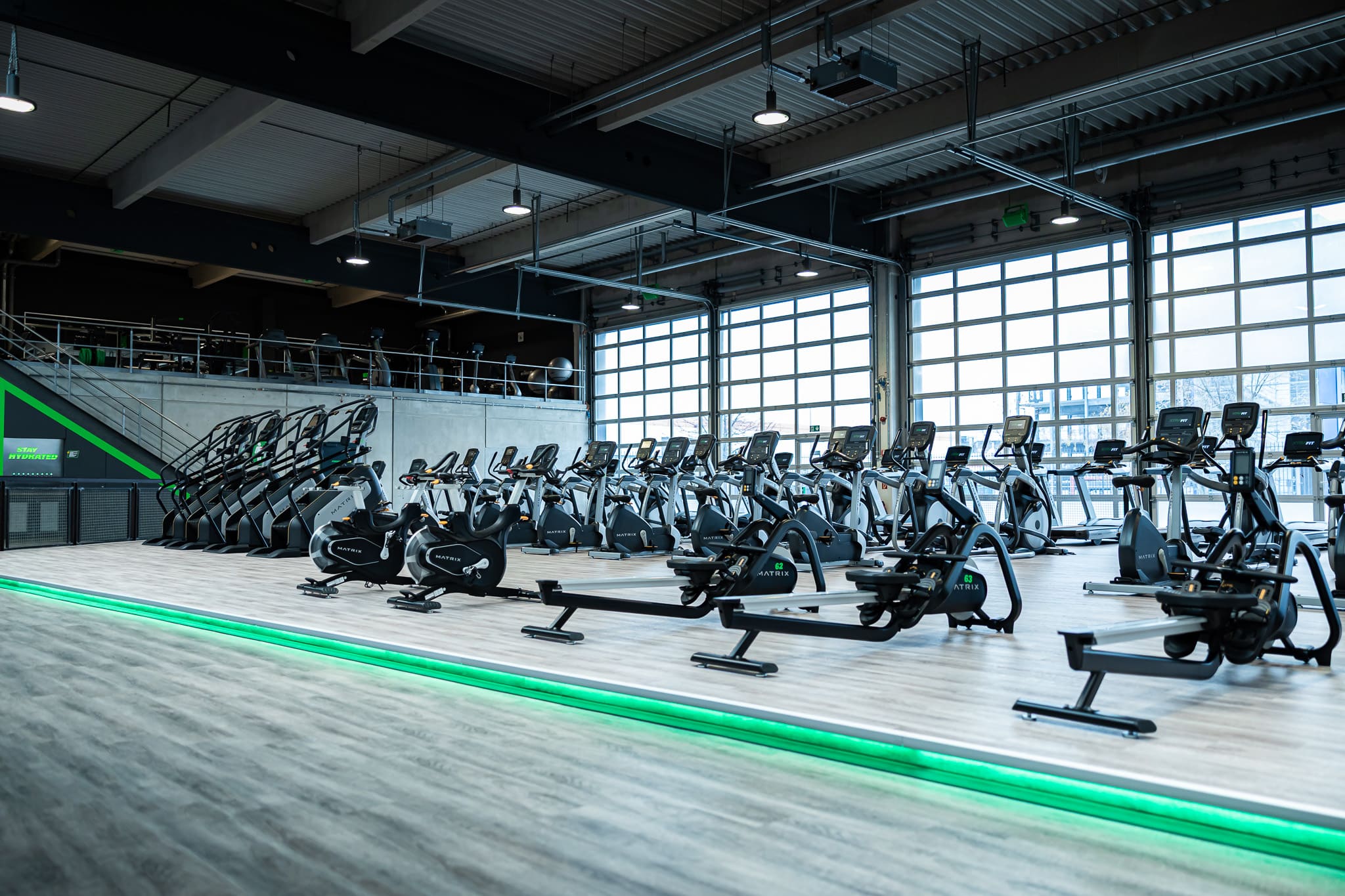 Cardio-Bereich im XTRAFIT Köln-Ossendorf mit großer Fensterfront und verschiedenen Trainingsgeräten.