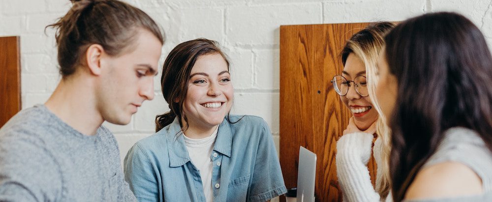 Group of young adults collaborating and smiling in a casual setting.