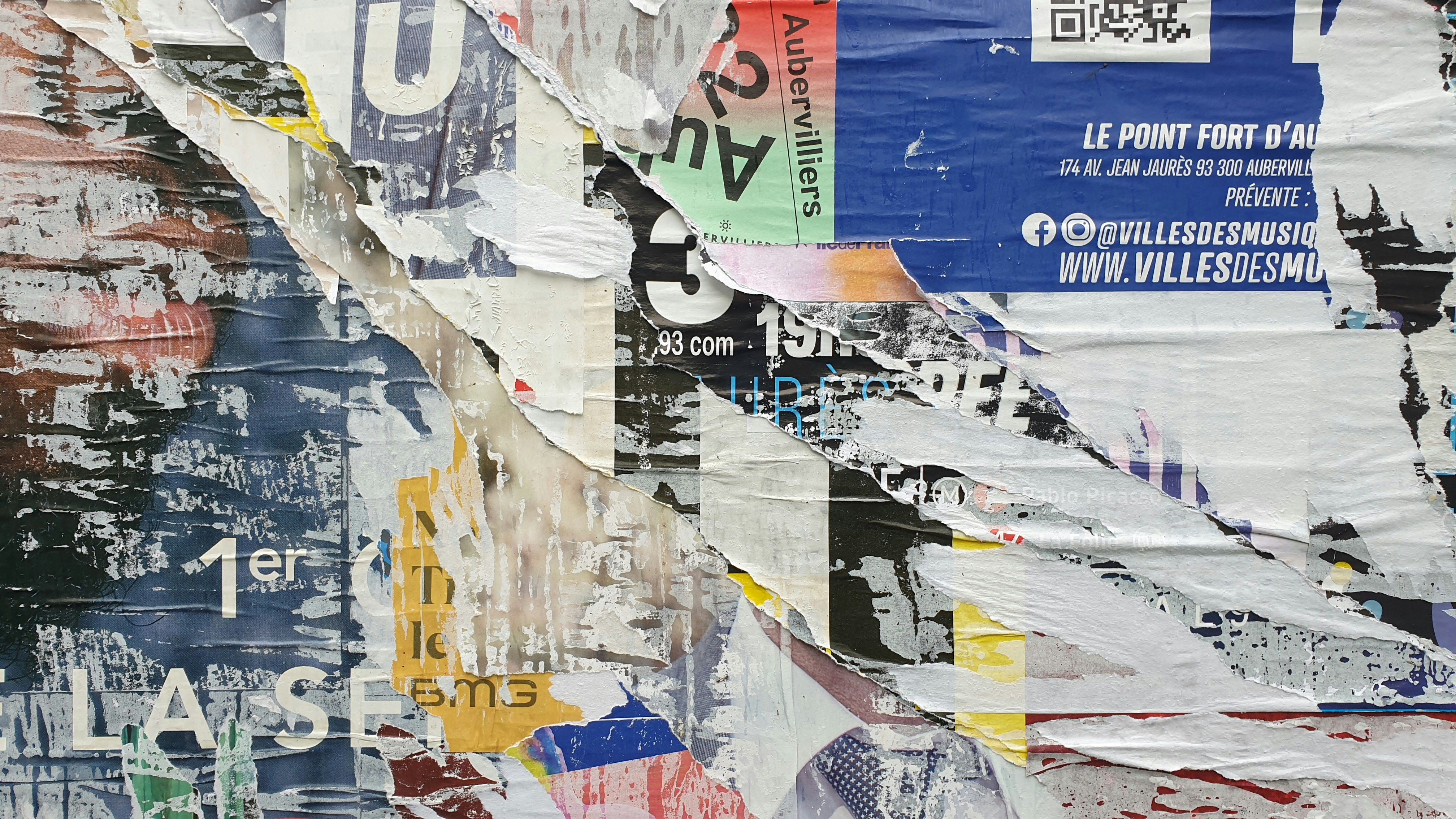 a bunch of torn up posters on a wall