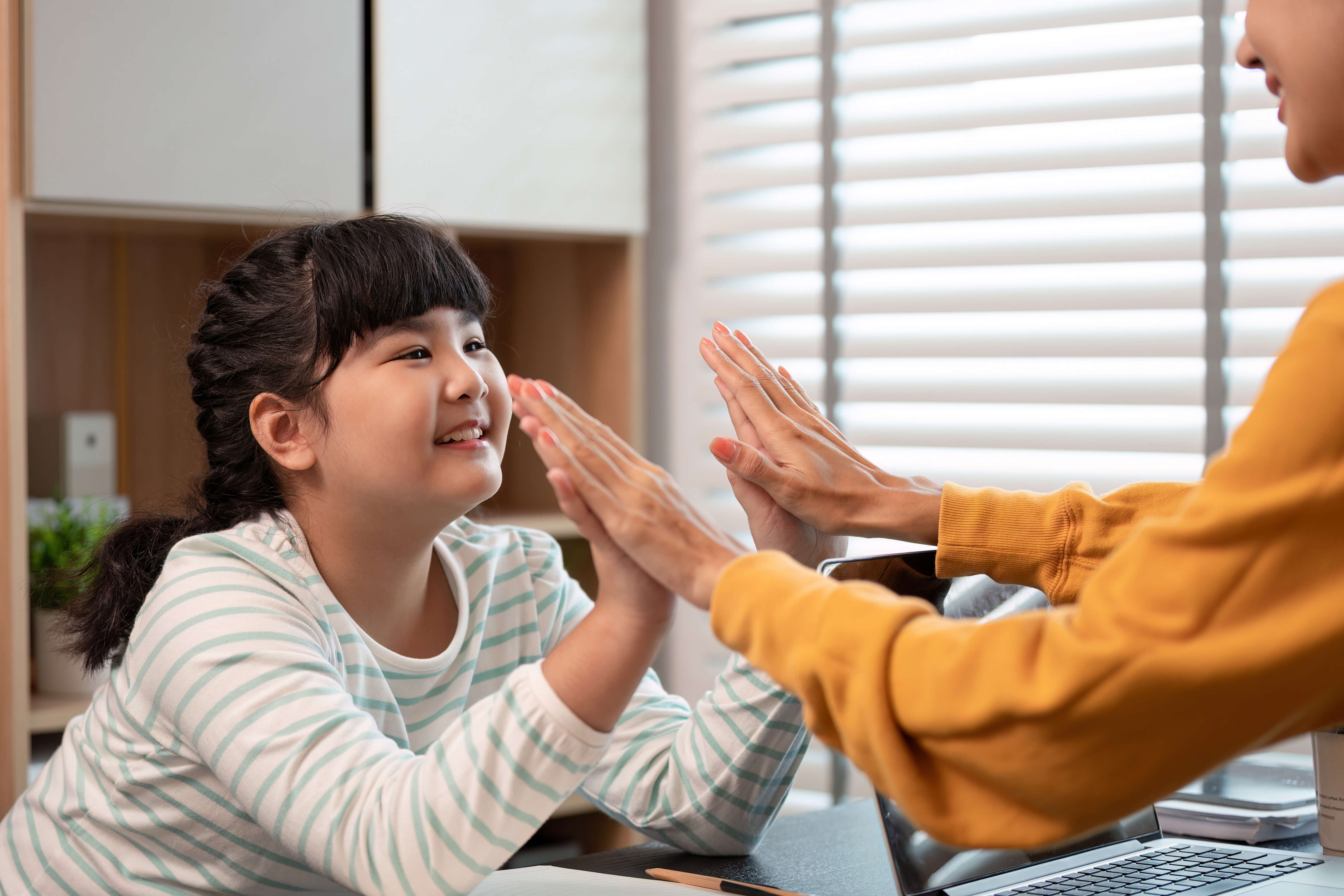 Two schoolgirls holding books are talking near a school building
