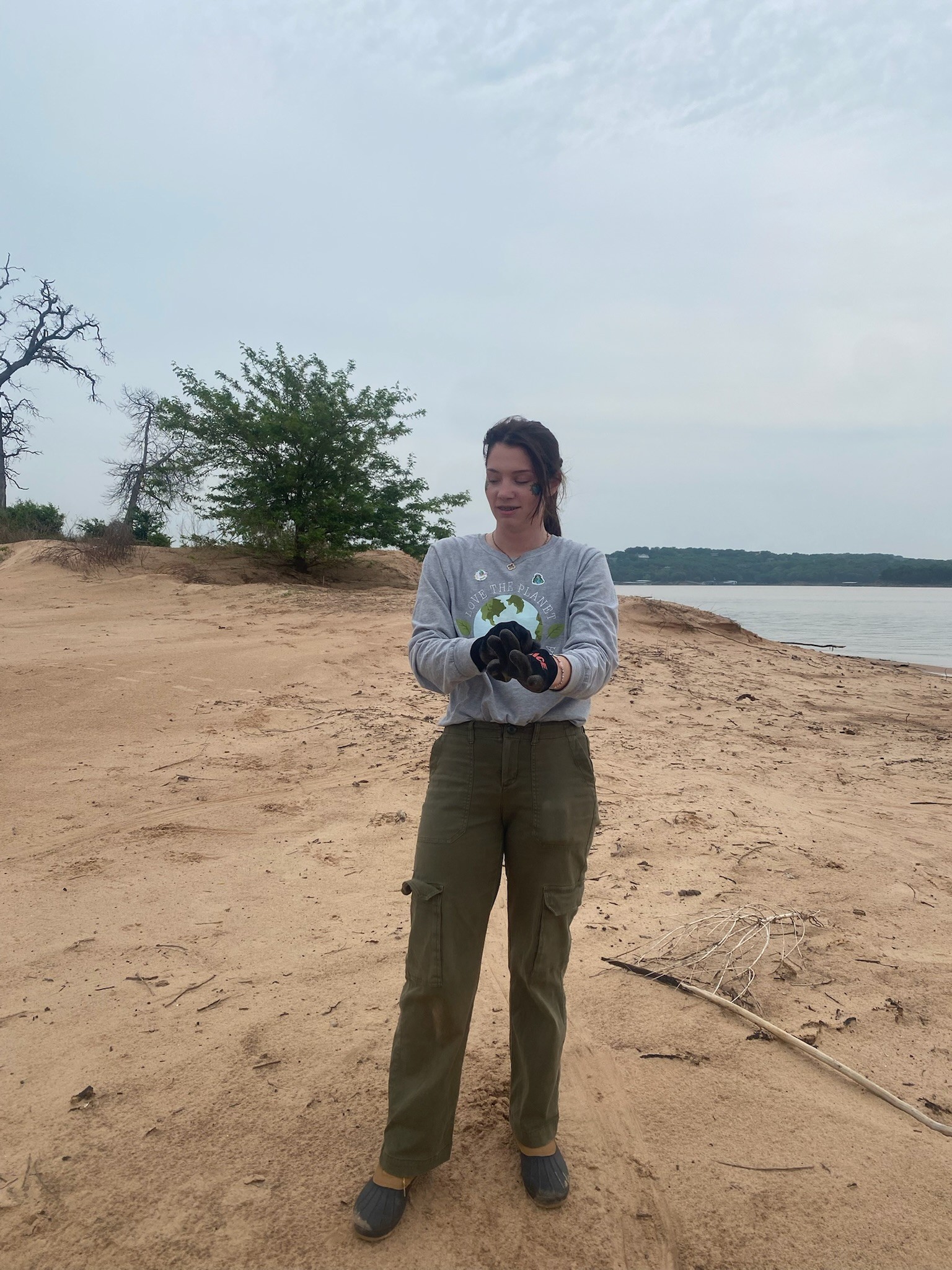Volunteers cleaning up trash on a beach by the water.